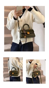 Detail of glossy olive green vintage leather bag with gold buckle and woven charm
