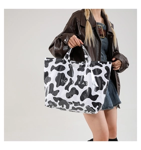 Detail of trendy cow print PVC tote bag with large capacity and double handles