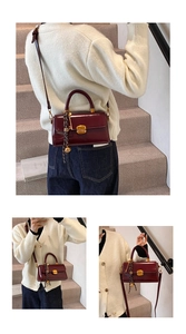 Detail showing burgundy gloss leather handbag with gold square lock and metallic ball charm