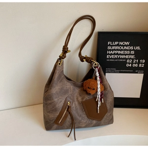 Vista dettagliata della borsa tote marrone con texture vintage, tracolla annodata e ciondolo