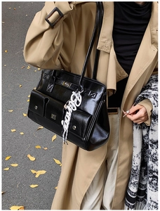 Detailed view of black vintage messenger bag featuring silver buckles and decorative charm