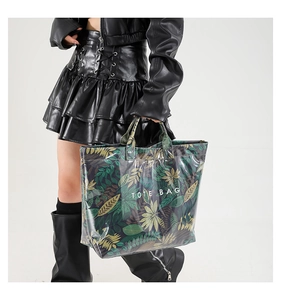 Fashionable tote bag with tropical leaf pattern shown on a model in a studio setting