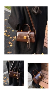 Detail view of a vintage dark brown leather crossbody bag with a golden square push lock