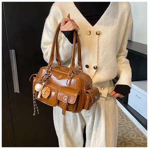 Detail of a brown glossy PU bowling bag with baseball charms and gold zipper accents