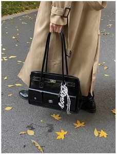 Close-up of black retro messenger bag with silver twist lock and dual front utility pockets