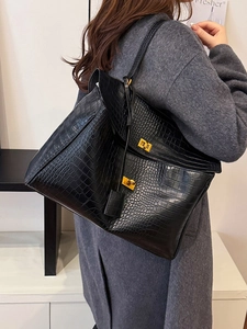Elegant black crocodile pattern tote bag with gold lock shown on model shoulder