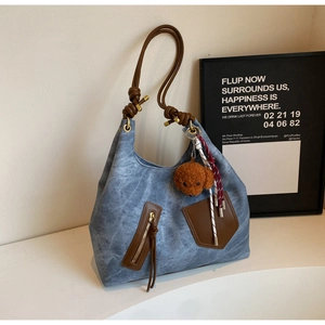 Dettaglio della borsa tote blu testurizzata con finiture in pelle marrone e ciondolo cane