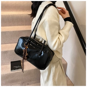 Détail du sac Boston en cuir verni noir avec charm de clé décoratif et fermeture
