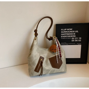 Dettaglio borsa tote beige con cinturini in pelle marrone e ciondolo a cucciolo