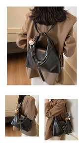 Detail of black leather backpack showing adjustable straps and baseball charm accessory