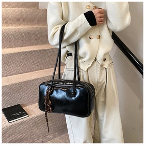 Détail d'un sac Boston en cuir ciré noir brillant avec un pendentif à franges tressées élégant
