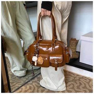 Detail view of glossy brown vintage bowling bag with functional pockets and baseball charm