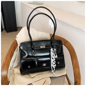 Close-up of black glossy satchel with silver buckle straps and a decorative printed scarf