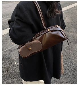 Detailed side view of deep brown glossy leather baguette bag with a mini pouch charm