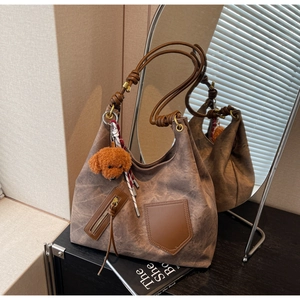 Dettaglio della borsa tote in tela marrone con manici in pelle e ciondolo cane