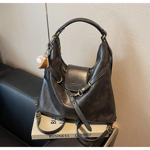 Detail shot of the dark brown leather shoulder bag with gold clasp and baseball charm