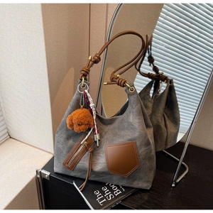 Dettaglio della borsa tote grigio scuro con tasche in pelle marrone e charm a cane