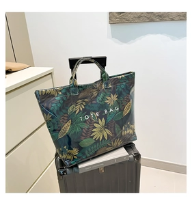 Macro view of water-resistant PVC tote bag with tropical leaf print on luggage