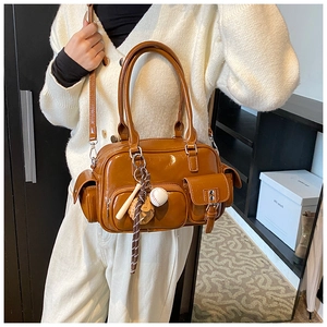 Caramel retro bowling bag shown as a side shoulder bag with a sporty baseball charm