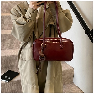 Détail du sac Boston vintage en cuir ciré bordeaux avec un charmant boulier doré