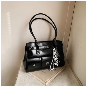 Close-up of black patent leather briefcase tote bag with silver square twist lock and strap