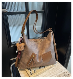 Detail of vintage brown hobo bag with zip pocket, plush bear charm and ribbon decor