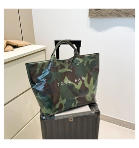 Detail of camouflage PVC tote bag with glossy finish on a suitcase for travel scene