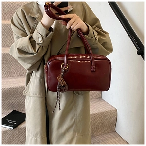 Détail du sac Boston vintage en cuir ciré bordeaux avec anneaux dorés et ruban décoratif
