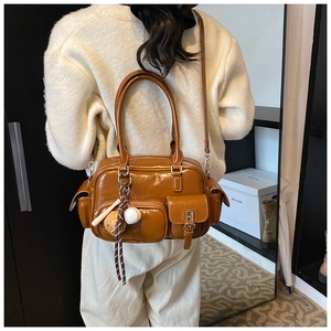 Brown retro PU leather bowling bag with baseball charms shown on shoulder by a model