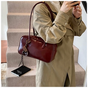 Détail du sac Boston en cuir ciré bordeaux avec un élégant pendentif à pampilles tressées