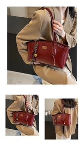 Detail view of burgundy leather tote bag featuring gold bell pendant and knotted strap