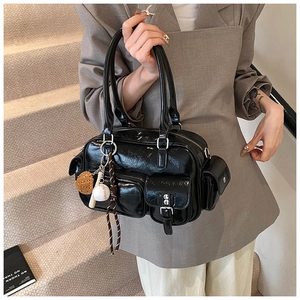 Close-up of black glossy leather bowling bag with multiple utility pockets and silver hardware