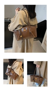Detail of oil wax leather tote bag featuring a gold fashion plaque and knotted straps