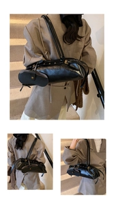 Detail of black oil wax leather baguette bag with gold hardware and mini pendant