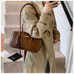 Détail du sac Boston en cuir ciré marron caramel avec pendentif tissé à nœuds