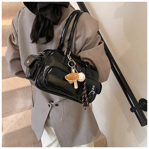 Detail view of black patent leather bowling bag featuring multiple pockets and baseball charm