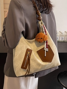Elegante borsa tote in tela beige con tasche in pelle marrone e ciondolo a orso