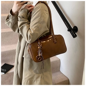 Détail du sac Boston vintage en cuir ciré marron avec breloque décorative de clé en métal