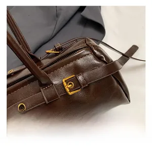 Close-up of the vintage oil wax leather texture and gold hardware on the dark brown bag