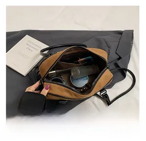 Macro view of the spacious inner compartment with zippers in a brown suede handbag