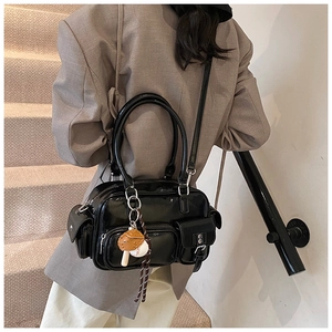 Detail of a black glossy bowling bag with multiple pockets and a baseball glove pendant charm