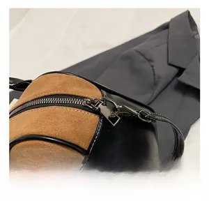 Detail of brown suede and black leather stitching with gunmetal hardware on handbag