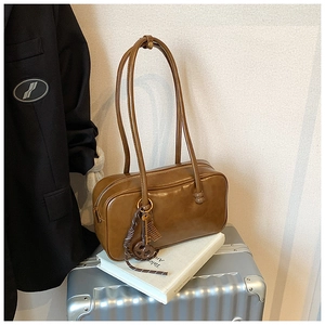 Détail du sac Boston en cuir ciré marron caramel avec pendentif en cordelette tressée