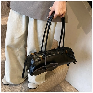 Detail of a black oil wax leather baguette bag with gold hardware held on stairs