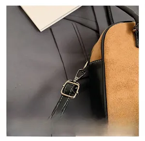Close-up of adjustable black leather shoulder strap with silver buckle on suede handbag