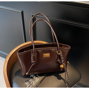 Detail view of smooth oil wax leather tote bag with metallic logo and knot accents