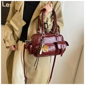 Detail of burgundy PU leather Boston bag featuring cargo pockets and baseball charms