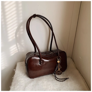 Vue détaillée d'un sac Boston vintage en cuir ciré marron foncé avec un pendentif clé doré