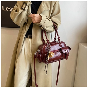 Detail of burgundy glossy Boston bag with multiple pockets and a cute bear charm
