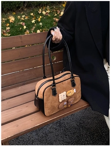 Detail of vintage brown suede pillow bag with cute cookie appliques on a park bench